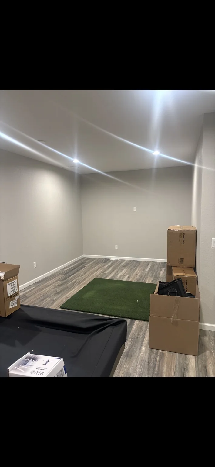 Basement room before SIMHAUS golf simulator installation, with flooring, hitting mat and equipment boxes