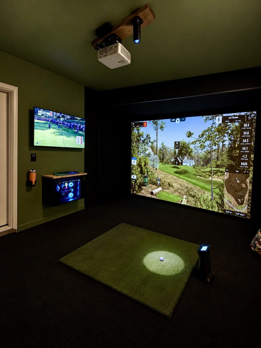 Completed garage golf simulator with green walls, black impact enclosure, projector and hitting mat